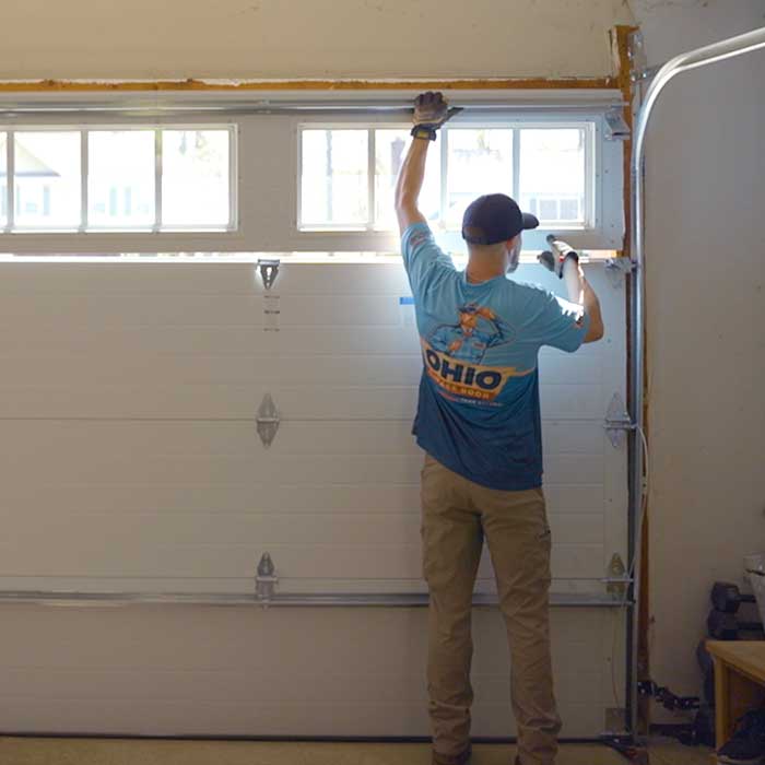 Garage Door Repair Service in Mentor, OH An Ohio Garage Door Repair technician is using a drill to fix a garage door spring near Mentor, OH