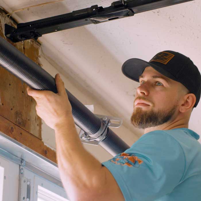 An Ohio Garage Door Repair technician is fixing a broken garage door spring near Youngstown, OH